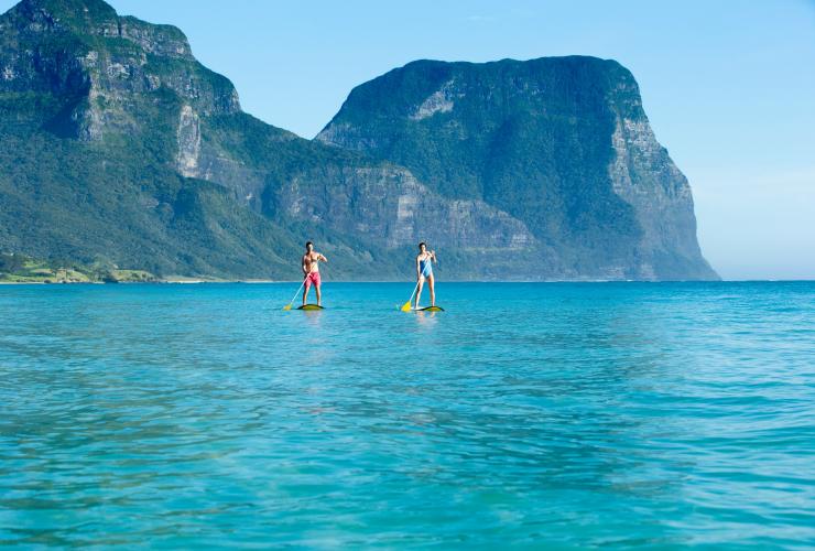 一对情侣在豪勋爵岛的潟湖海滩享受立式单桨冲浪 © 新南威尔士州旅游局版权所有