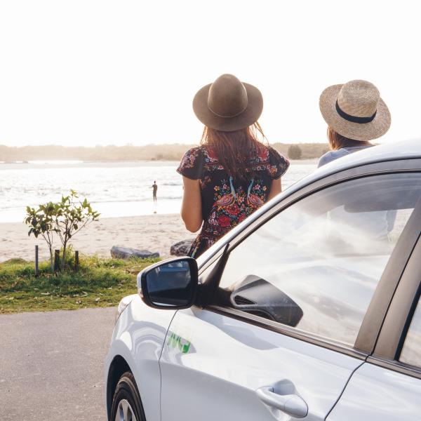 努沙，两个坐在 Jucy 车前排的女孩看着海滩 © Jucy 版权所有