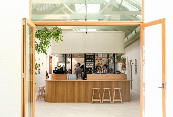 南澳大利亚州，阿德莱德，光线充足的 Bloom 咖啡馆，咖啡师在木制吧台后忙碌 © Bloom 版权所有