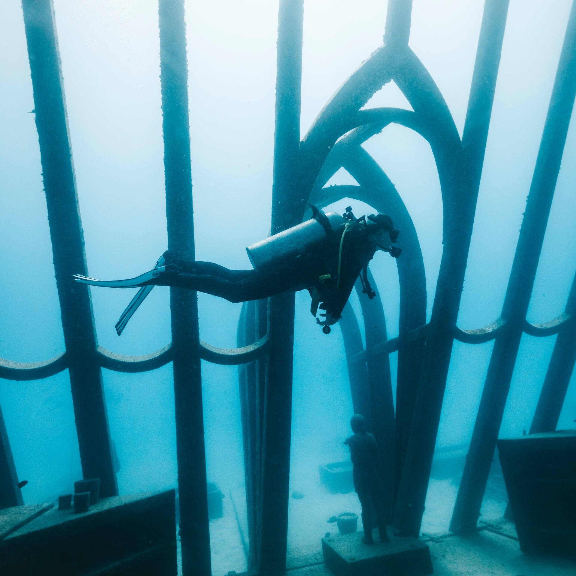 一名水肺潜水员在水下艺术博物馆珊瑚温室内的雕塑旁边潜游 © Gemma Molinaro 摄影师版权所有