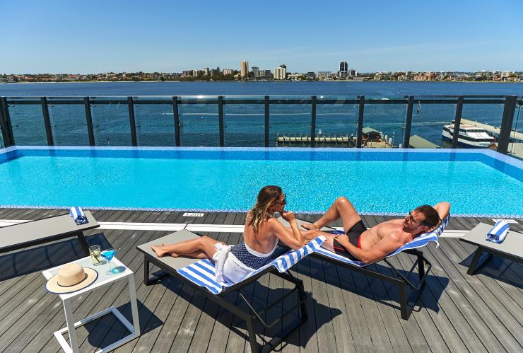 西澳大利亚州，珀斯，在海滨希尔顿逸林酒店的屋顶泳池晒日光浴的情侣 © 海滨希尔顿逸林酒店版权所有