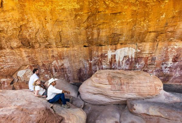 昆士兰州，库克，Jarramali 岩画之旅，两名旅客与原住民向导坐在一起，欣赏古老的岩画 © 澳大利亚旅游局版权所有