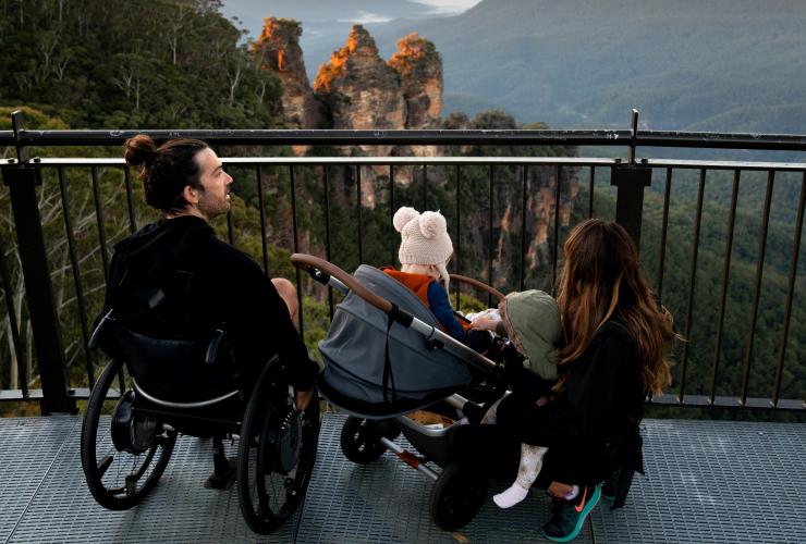 新南威尔士州，蓝山，一位坐轮椅的男子及其家人一起观赏三姐妹峰 © 澳大利亚旅游局版权所有