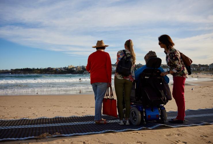 新南威尔士州，悉尼，邦迪海滩，一位坐轮椅的男子及其家人参加澳大利亚风尚旅行社的项目 © 新南威尔士州旅游局版权所有