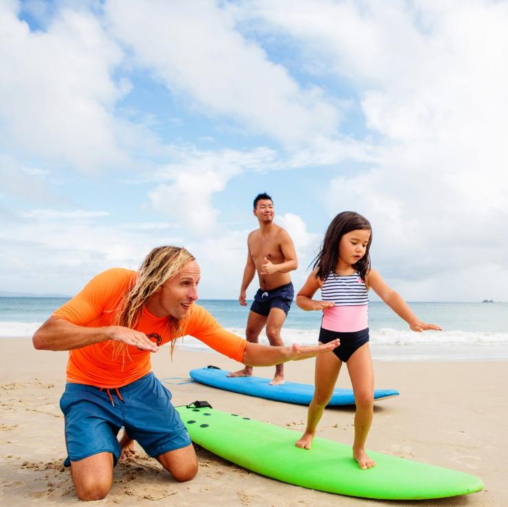 在拜伦湾克拉克斯海滩（Clarkes Beach）学习冲浪的家庭。© 新南威尔士州旅游局版权所有