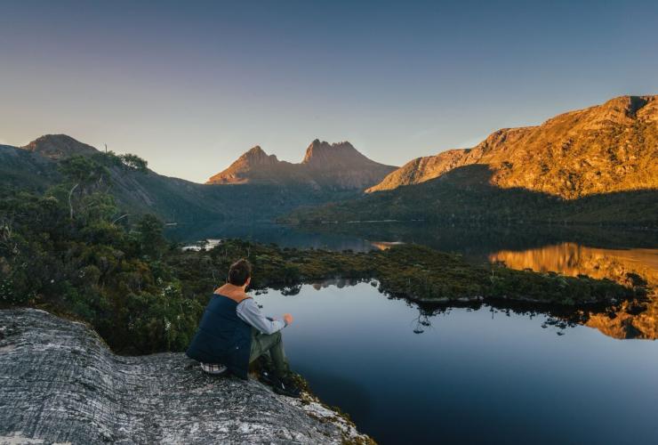 沿着摇篮山小屋步道（Cradle Mountain Huts Walk）欣赏摇篮山日落景象的男子 © 塔斯马尼亚旅游局版权所有