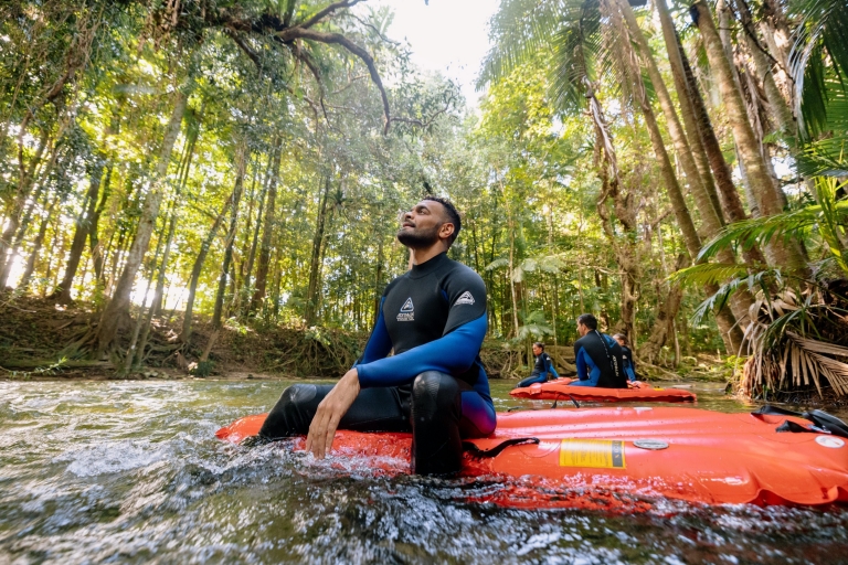 昆士兰州，一名男子坐在 Back Country Bliss Adventure 公司提供的浮筏上，他一边在河面上漂流，一边仰望着戴恩树热带雨林翠绿的雨林树冠 © 澳大利亚旅游局版权所有