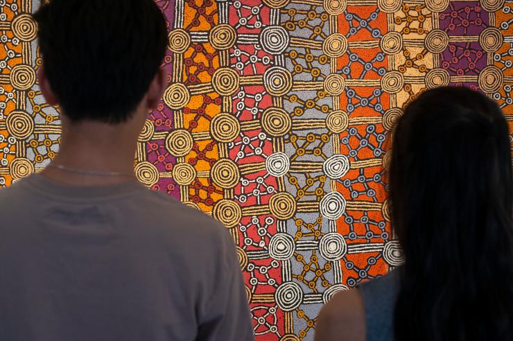 北领地，爱丽斯泉，Papunya Tula 美术馆，一对情侣站在一幅彩色点画前 © 北领地旅游局/Rhett Hammerton 版权所有