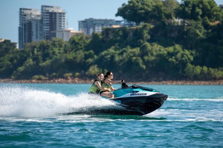 北领地，在 007 摩托艇冒险之旅（00Seven Jet Ski Adventures Tour）中，两人开着摩托艇在海上驰骋，背景中是达尔文 © 北领地旅游局版权所有