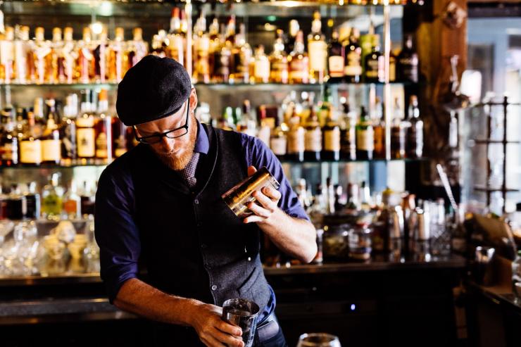 塔斯马尼亚州，霍巴特，亨利琼斯艺术酒店，在 IXL 长廊酒吧的一排酒类陈列架前，有一名手握调酒器的酒保 © The Henry Jones/Adam Gibson 版权所有