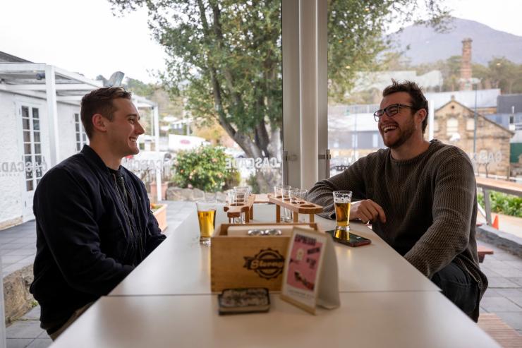 塔斯马尼亚州，霍巴特，凯歌啤酒厂，两名男性坐在桌前畅饮啤酒 © 澳大利亚旅游局版权所有