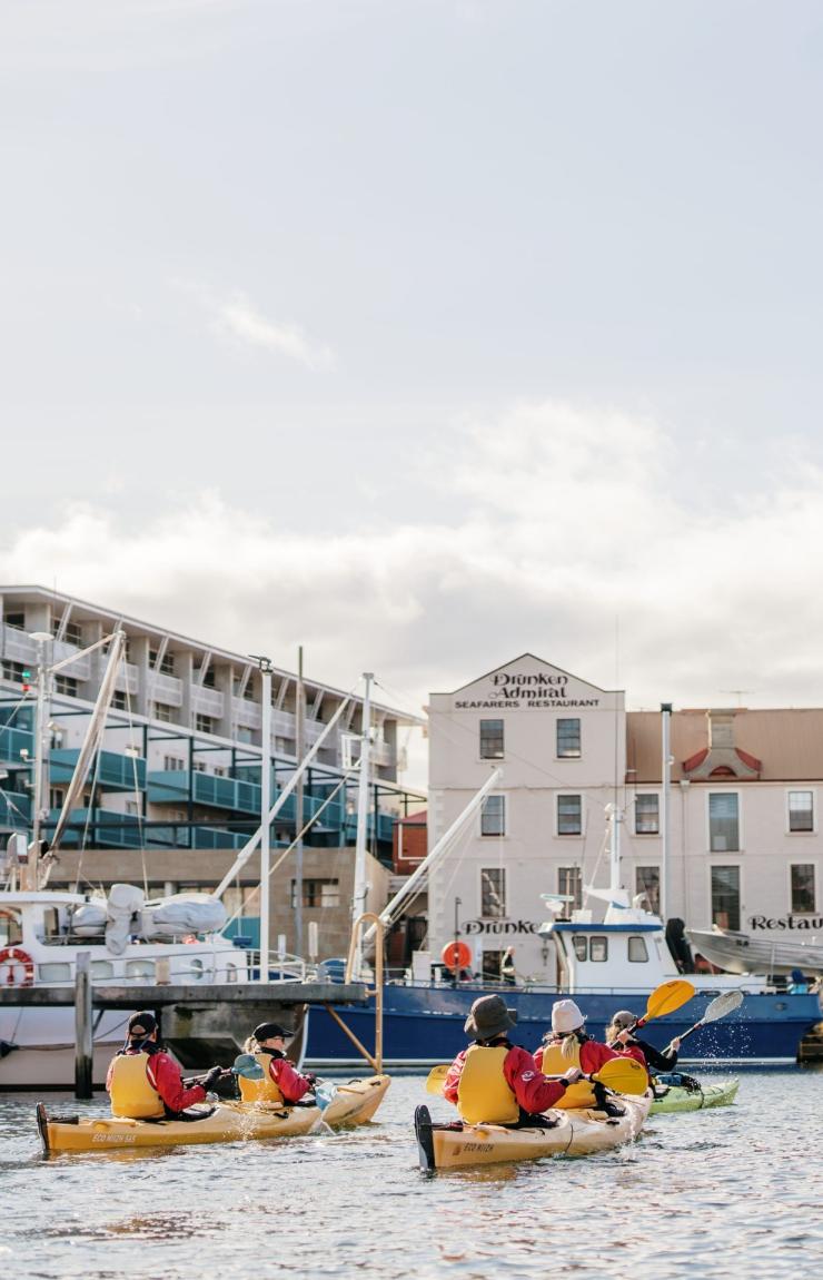 塔斯马尼亚州，霍巴特，参加 Roaring 40s Kayaking 旅游团的一行人划着黄色皮艇穿行在码头的船只间 © 澳大利亚旅游局版权所有