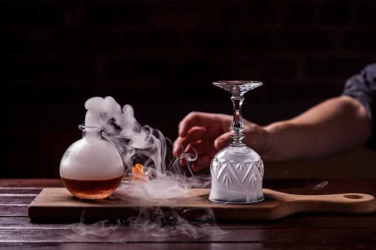 维多利亚州，墨尔本，Eau De Vie 酒吧，一只手伸向冒着烟的鸡尾酒的特写 © 墨尔本美食美酒节版权所有