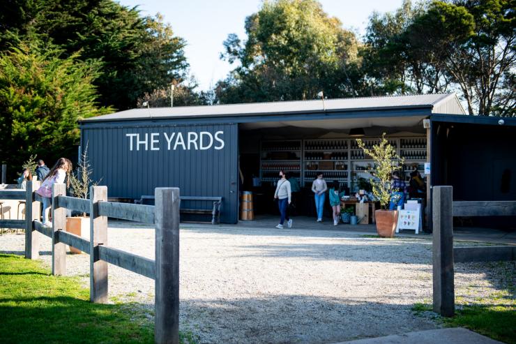 维多利亚州，菲利普岛，菲利普岛酒庄 The Yard 商店外观，开放的建筑有人在进出，四周绿树环绕 © Adeline & Lumiere / 维多利亚州旅游局版权所有