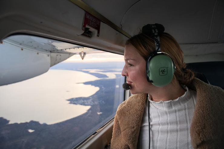 塔斯马尼亚州，在乘坐 Freycinet Air 观光飞机飞行在菲欣纳国家公园上空时，一位女性戴着耳机，向机窗外眺望 © 澳大利亚旅游局版权所有