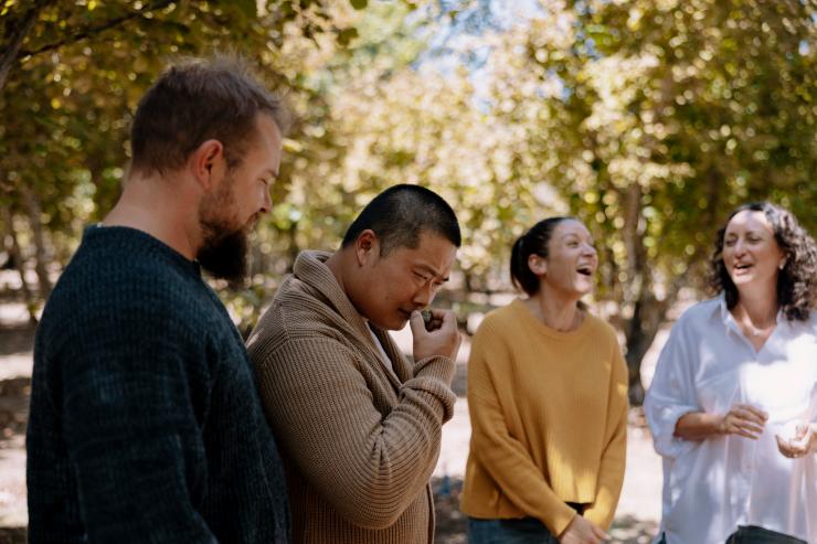 西澳大利亚州，曼吉马普，松露山，旅游团中的一名男子在闻松露的味道，旁边还有其他几名游客 © 澳大利亚旅游局版权所有