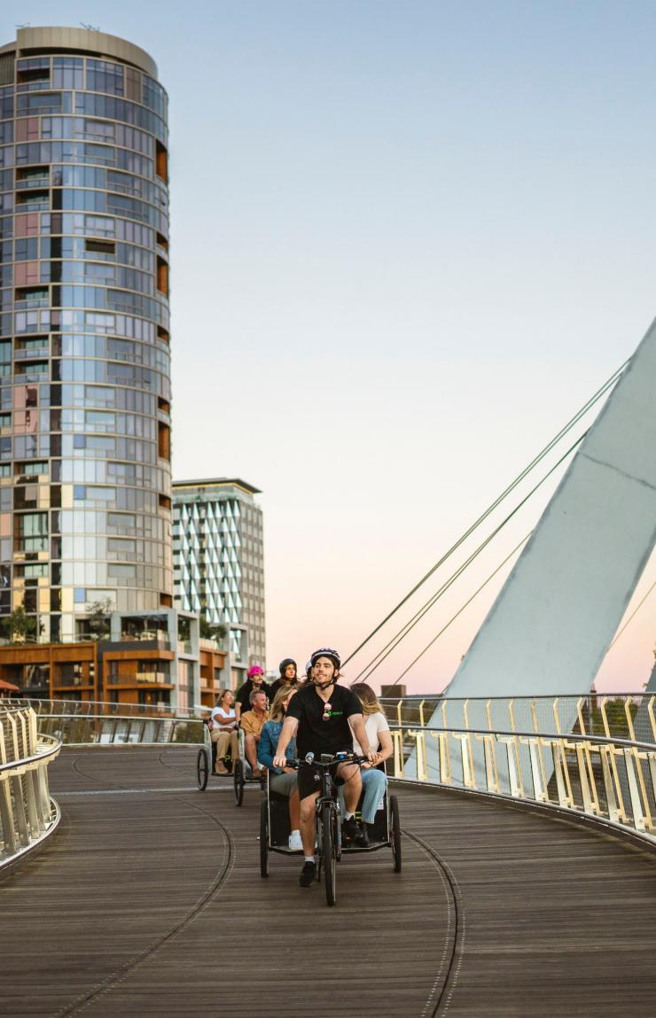 西澳大利亚州,珀斯,参加 Peddle Perth 的一群游客在夜晚乘坐三轮车穿越大桥 © 澳大利亚旅游局版权所有 西澳大利亚州,珀斯,参加 Peddle Perth 的一群游客在夜晚乘坐三轮车穿越大桥 © 澳大利亚旅游局版权所有