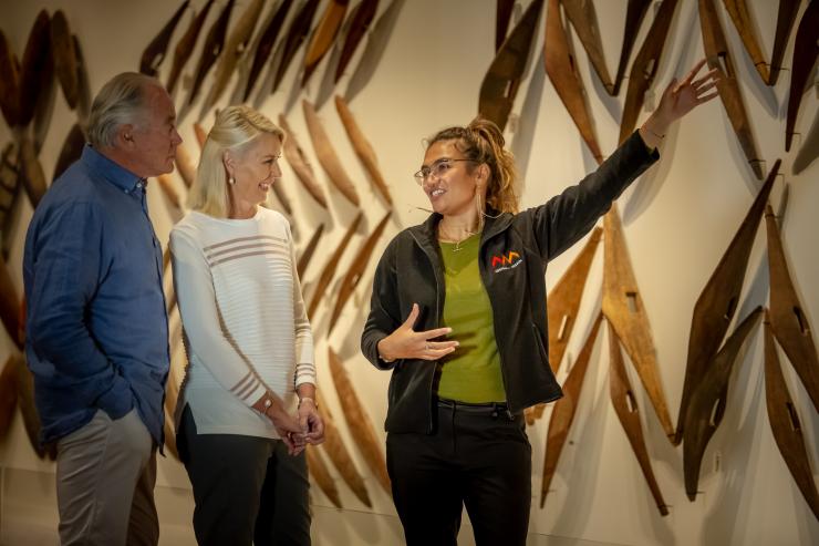 新南威尔士州，悉尼，一对情侣在参观“最早的澳大利亚人展馆”，导游指着墙上的木制文物为他们解说 © 澳大利亚旅游局版权所有