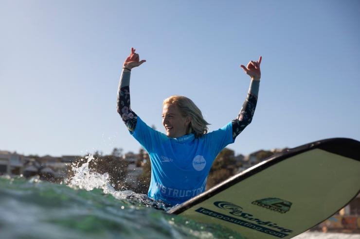 新南威尔士州，邦迪海滩，“海滩冲浪之旅”课上一个人驾着浪板在冲浪，手臂展开以保持平衡 © 新南威尔士州旅游局版权所有