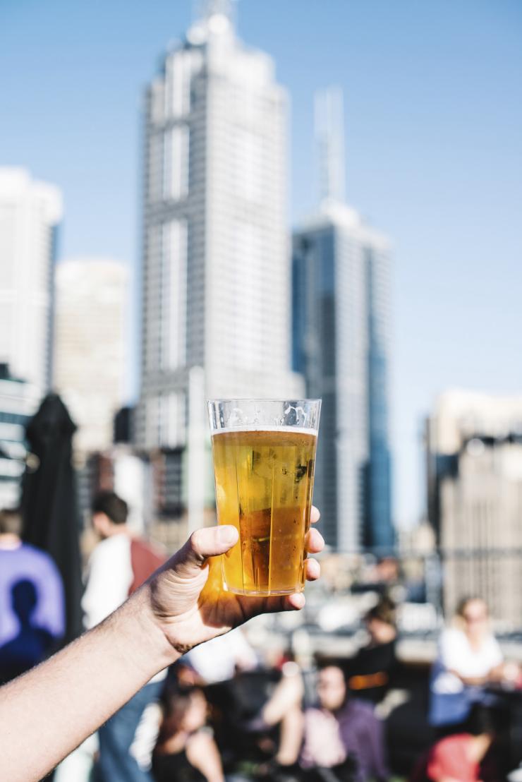 在墨尔本的屋顶酒吧手握一杯啤酒 © 澳大利亚旅游局版权所有