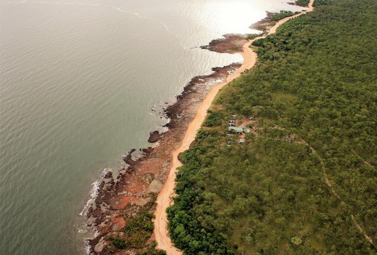 北领地，阿纳姆地区，Dhipirri Barra 游钓旅舍，崎岖海岸线上一个钓鱼小屋的航拍图，周围环绕着原始林地 © Dhipirri Barra 游钓旅舍版权所有