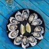 塔斯马尼亚州，布鲁尼岛，俯瞰 Get Shucked 餐厅蓝色餐桌上的一盘生蚝，生蚝围绕中间的柠檬片摆成圆形 © Adam Gibson / 塔斯马尼亚旅游局版权所有