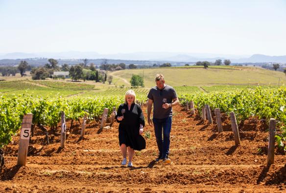 新南威尔士州，猎人谷，天瑞酒庄，两个人手捧酒杯，漫步在葡萄园中 © 新南威尔士州旅游局版权所有