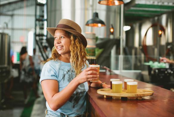 新南威尔士州，拜伦湾，一位女性在石头和木头啤酒厂品尝啤酒 © 新南威尔士州旅游局，James Horan 版权所有