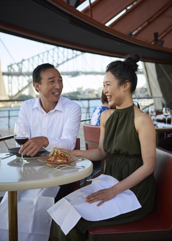 新南威尔士州，悉尼，Bennelong 餐厅，一对情侣正在享用午餐，海港美景尽收眼底 © 新南威尔士州旅游局版权所有