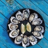 塔斯马尼亚州，布鲁尼岛，俯瞰 Get Shucked 餐厅蓝色餐桌上的一盘生蚝，生蚝围绕中间的柠檬片摆成圆形 © Adam Gibson / 塔斯马尼亚旅游局版权所有