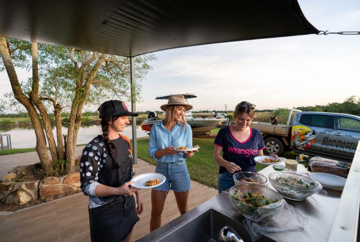 北领地，百丽泉，参加 Barramundi Adventures Darwin 旅游团的三个人在挑选自助餐食，身后是水道和船只 © 澳大利亚旅游局版权所有