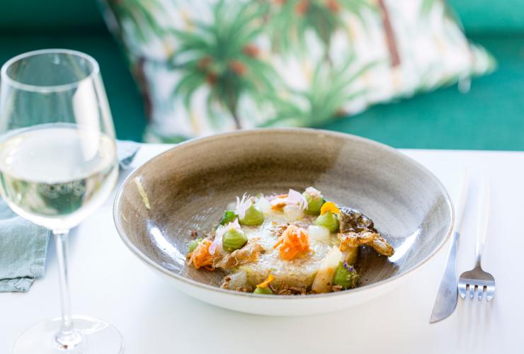 北领地，达尔文，鲷鱼岩，一道色彩丰富的菜肴，旁边配有一杯白葡萄酒 © 北领地旅游局版权所有