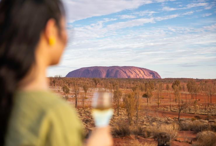 北领地，乌鲁鲁，寂静之声晚宴，一人手持酒杯，望着一块红色单体巨岩 © 北领地旅游局/Helen Orr 版权所有