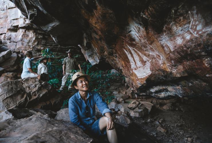 北领地，卡卡杜国家公园，参加卡卡杜文化之旅旅游团的一群人在一边欣赏原住民岩画艺术一边交谈 © 澳大利亚旅游局版权所有