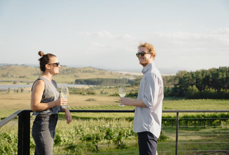 澳大利亚首都领地，马德拉山葡萄园，Cubby and Co 豪华露营，两个人在阳台上品酒，俯瞰着绿意盎然的葡萄园 © 澳大利亚旅游局版权所有