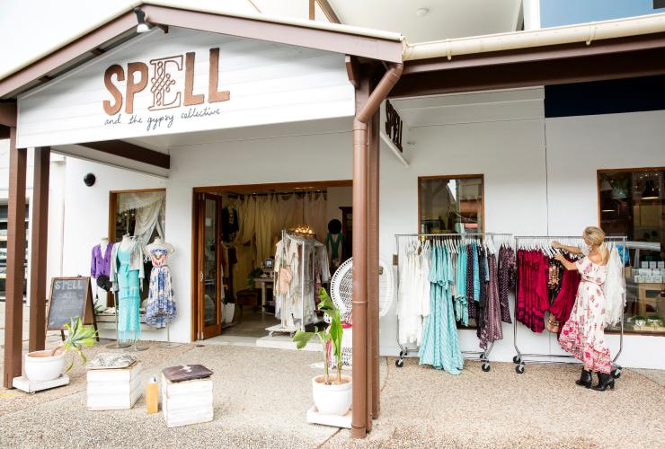 新南威尔士州，拜伦湾，Spell & The Gypsy Collective，一个人正在一家别致的波西米亚风店门外，对着一排衣服挑挑选选 © 新南威尔士州旅游局版权所有