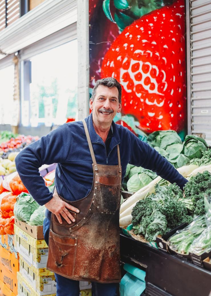 澳大利亚首都领地，堪培拉，Fyshwick Fresh Food Markets，商贩微笑地看着摊位旁的镜头 © Fyshwick Fresh Food Markets 版权所有